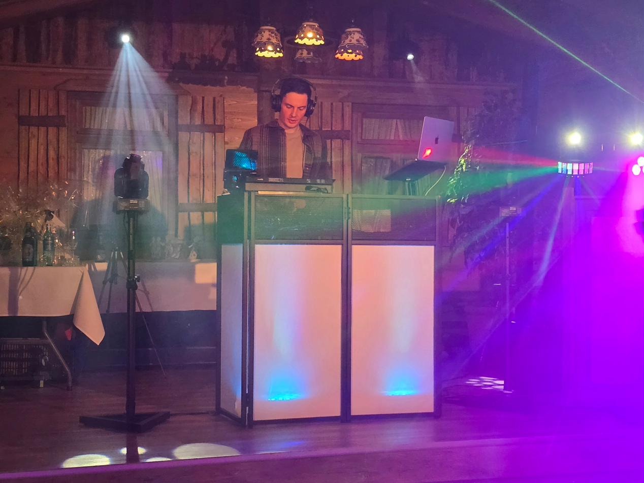 DJ Markus Holder am beleuchteten Pult mit Lichtshow und Nebel bei einer Feier